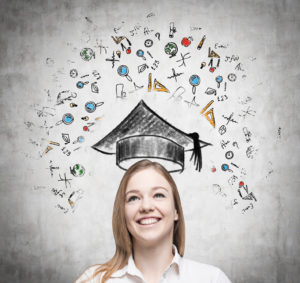 Young beautiful lady is thinking about studying at the university. Educational icons are drawn on the concrete wall.